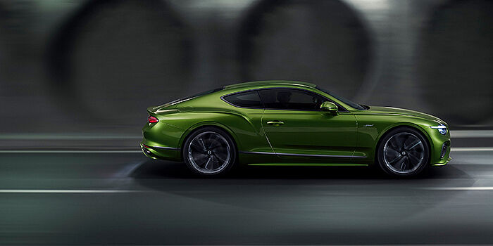Bentley Phnom Penh Bentley Continental GT coupe in Tourmaline Green paint driving in profile on a dark road
