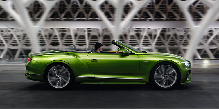 Bentley Phnom Penh Bentley Continental GTC Speed convertible side profile in Tourmaline Green paint driving dynamically on a bridge at night