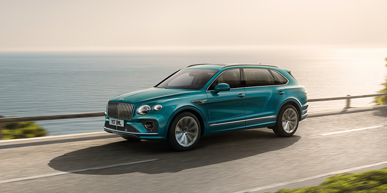 Bentley Phnom Penh Bentley Bentayga Extended Wheelbase Azure SUV in Topaz blue paint driving dynamically by the ocean