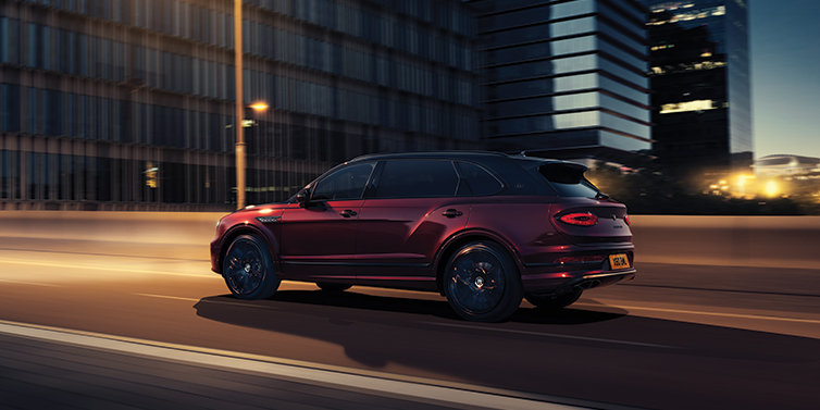 Bentley Phnom Penh Bentley Bentayga Extended Wheelbase Mulliner SUV in Cricket Ball red paint driving dynamically in city at night